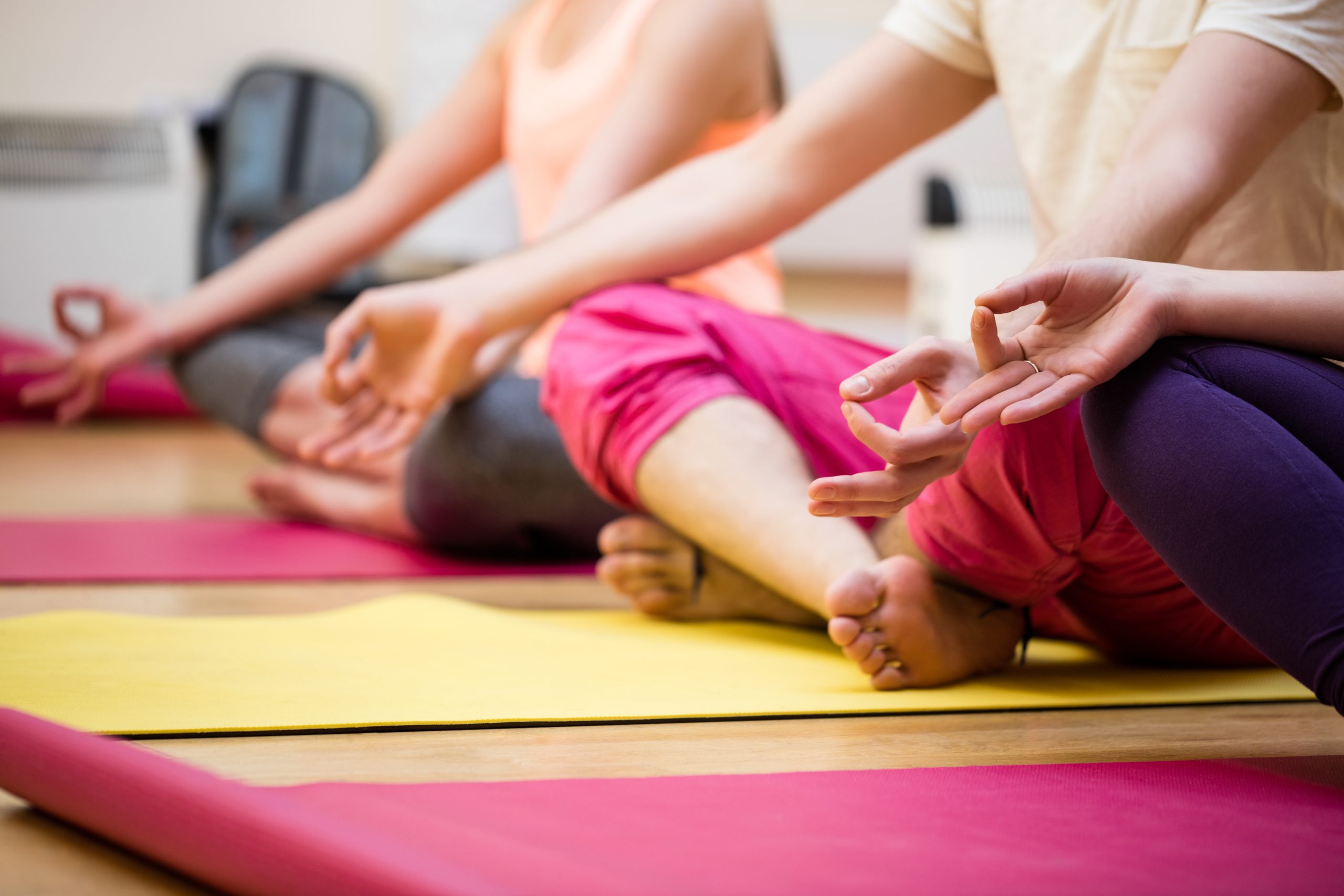 Group of people sitting in lotus position in the fitness studio